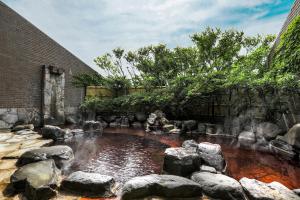 a pond with rocks in front of a building at Hotel Yubana in Hakui