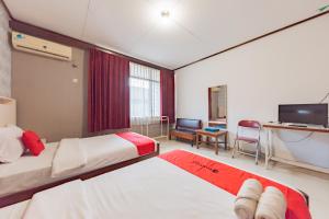 a hotel room with two beds and a tv at RedDoorz Syariah at Hotel Budi Family in Ciamis