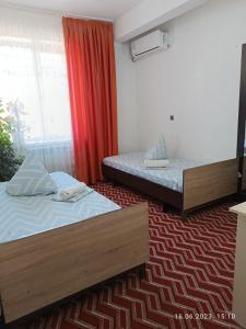 a bedroom with two beds and a red curtain at HalalHostel in Osh