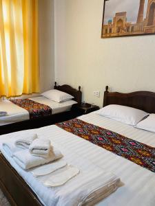 two beds in a hotel room with towels on them at Elegant Family Hotel in Tashkent