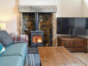 a living room with a fireplace and a couch at Corner Cottage in Great Longstone