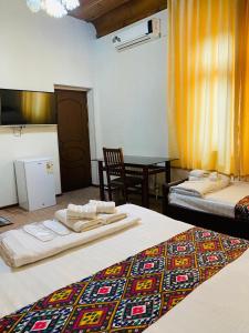 a hotel room with two beds and a table with a table at Elegant Family Hotel in Tashkent