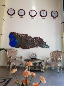 a wall with clocks and a table and chairs at Hotel Argo in Batumi
