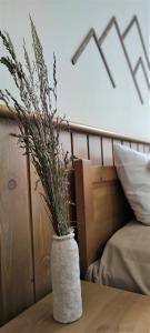 Pirin Golf & Spa Greenside Studio في رازلوغ: مزهرية بيضاء مع زرع يجلس على طاولة
