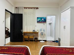 a bedroom with two beds and a desk with a fan at Dalat ECO Hotel 2 in Da Lat