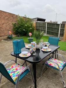 a black table with chairs and plates and cups at Beautiful 2-bedroom in Grays close to Lakeside in Grays Thurrock