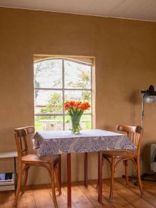 un tavolo con un vaso di fiori sopra di una finestra di Willem's Huisje a Laren