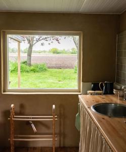 a kitchen with a sink and a window at Willem's Huisje in Laren