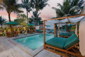 a resort pool with lounge chairs and umbrellas at Horison Ume Suites & Villas in Ubud