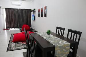 a dining room table and chairs with a red pillow on it at Two Bed Rooms -Cahaya Homestay Tanjung Malim in Ulu Bernam