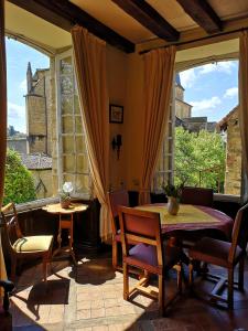 a dining room with a table and chairs and large windows at La Lanterne Chambres d'Hotes in Sarlat-la-Canéda