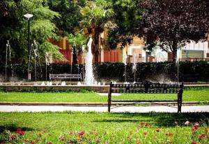 un parque con un banco y una fuente en Apartamento Valdepasillas en Badajoz