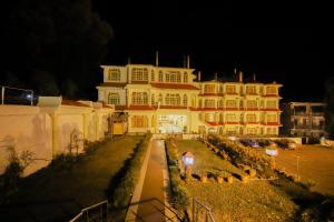 een groot wit gebouw met een tuin ervoor bij Royal Palace Resort Bhagsunag in Dharamshala