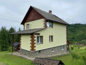 une grande maison jaune avec un toit marron dans l'établissement Родинна оселя, à Slavsko