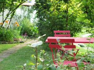 einem roten Tisch und einer Bank in einem Garten in der Unterkunft CHAMBRES D'HÔTES LA MADELEINE in Vienne-le-Château