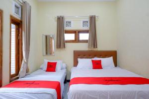 two beds in a room with red pillows at RedDoorz near Desa Wisata Tambi Dieng in Wonosobo