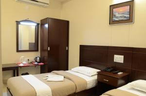 a hotel room with two beds and a mirror at Hotel Sky Lite in Coimbatore