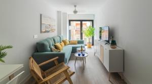 a living room with a blue couch and a tv at Bretón 17- Apartamentos con piscina climatizada en Alicante centro in Alicante