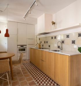 una cocina con armarios blancos, una mesa y una barra en Carmen del Azahar by Florentia Homes, en Granada