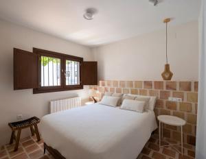 1 dormitorio con cama blanca y ventana en Carmen del Azahar by Florentia Homes, en Granada