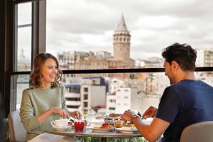 a man and a woman sitting at a table eating food at JW Marriott Istanbul Bosphorus in Istanbul