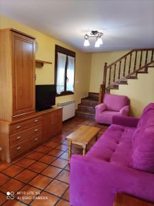 a living room with a purple couch and a staircase at Casa A Ruata in Torla-Ordesa