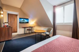パリにあるHoliday Inn Paris - Gare de Lyon Bastille, an IHG Hotelのベッドとテーブルが備わるホテルルームです。