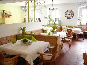 un restaurante con mesas y sillas blancas y ventanas en Apartments Erbgericht, en Bad Schandau