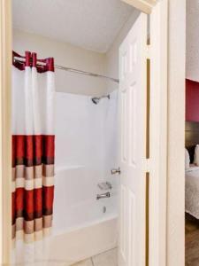 a bathroom with a tub and a shower curtain at American Inn in Corsicana
