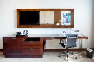 a desk with a television and a chair in a room at Courtyard by Marriott Pune Chakan in Chakan