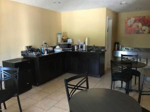 a kitchen with black cabinets and tables and chairs at American Inn in Corsicana