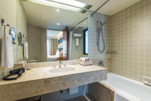 a bathroom with a sink and a tub and a mirror at Chatrium Residence Sathon Bangkok in Bangkok