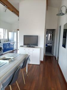 Una sala de estar con un televisor y una mesa con sillas. en Chalet La Mer Veille 1, en Gruissan
