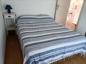 a bed with a blue and white striped blanket on it at Chalet La Mer Veille 1 in Gruissan