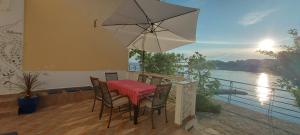 a table and chairs on a balcony with an umbrella at Kuća Ugor in Lun