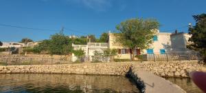 a house with a stone wall next to a body of water at Beachfront House Ugor in Lun