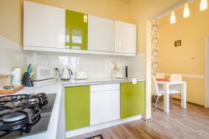 a kitchen with white and green cabinets and a stove at Pyvo Street Home with balcony near the Danube in Budapest