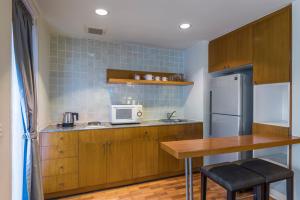 a kitchen with a table and a microwave and a refrigerator at Chatrium Residence Sathon Bangkok in Bangkok