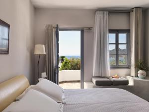 sypialnia z łóżkiem i dużym oknem w obiekcie The Petra w mieście Patmos