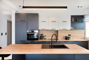 a kitchen with white cabinets and a wooden counter top at #Oddity seafront apartments in Thessaloniki