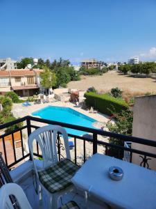 a balcony with a table and chairs and a swimming pool at Jasmin Gardens in Paphos City