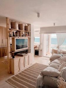 a living room with a tv and a couch at Umdloti Boho Beach Villa in Umdloti
