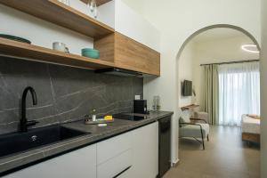 a kitchen with a sink and a room with a bed at Nόka Suite Apartments in Faliraki