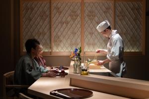 a chef preparing food at a counter in a restaurant at Hatago in Kobe