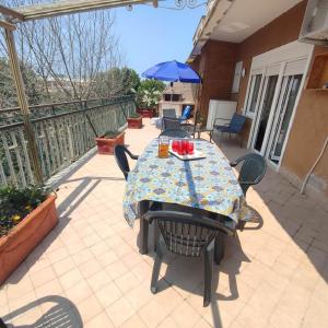 patio con tavolo, sedie e ombrellone di Attico Centrale Ostia 20 a Lido di Ostia