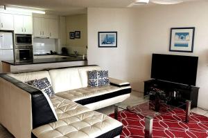 uma sala de estar com um sofá, uma mesa e uma televisão em 2 Bedroom Ocean View - Alexandria Apartments -Alexandra Headland em Maroochydore
