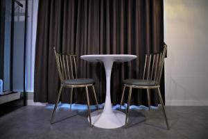 a white table and two chairs in front of a curtain at Brighton Hotel in Jeonju