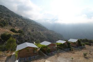 un grupo de chozas en una colina con una montaña en Pavlonya Bungalows en Mugla