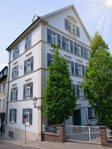 un bâtiment blanc avec un arbre devant lui dans l'établissement Ferienwohnung Baden Baden, à Baden-Baden