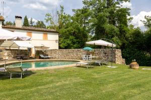 a pool in a yard with chairs and umbrellas at Casale Mulin Bianco in Monteriggioni